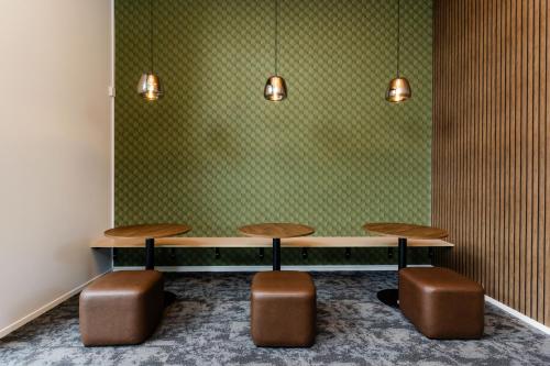 罗托鲁瓦Haka House Rotorua的绿墙纸的房间,设有两张桌子和两张凳子