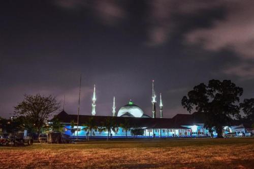 PorisgagaKoolKost near Stasiun Poris Tangerang的清真寺在晚上点燃,前面有一片田野