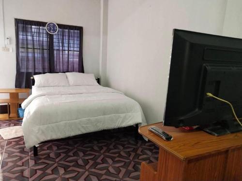Ban Hua ThaleChainarong Road的一间卧室配有一张床和一张桌子上的电视