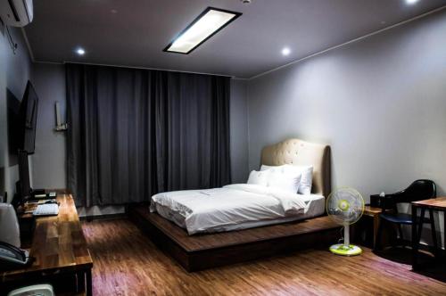 Heitz Hotel的一间卧室配有一张带白色床单的床和风扇