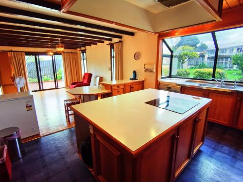 旺阿雷Denby Golf House Tikipunga的一个带岛屿的厨房和大窗户