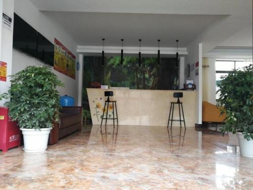 林芝Shell Linzhi Bayi Area G318 Shuangyong Road Hotel的一间房间,设有两张凳子和一个植物台面
