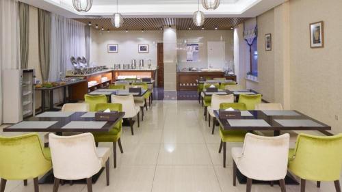 哈尔滨Floral Hotel Birch's Story Harbin的用餐室配有桌子和黄色椅子