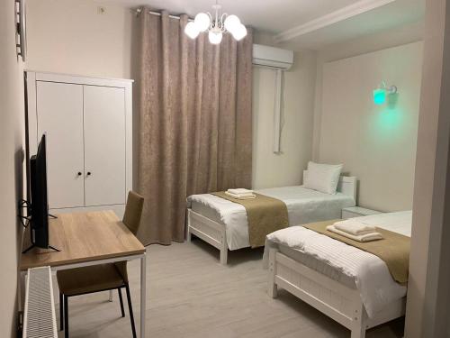 第比利斯Cultural Crossing Hotel的客房设有两张床、一张桌子和一张书桌。