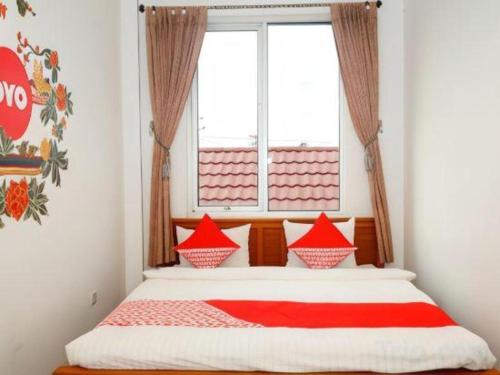 丹戎潘丹Hotel Meigah的窗户间里一张带红色枕头的床