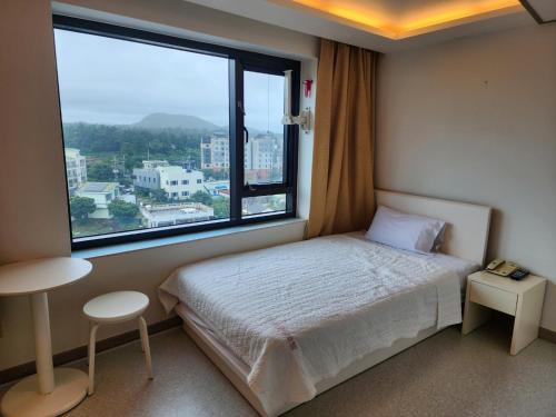 西归浦市瑞兹翁酒店的一间卧室设有一张床和一个大窗户