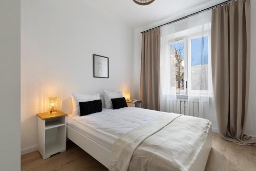 格但斯克Elite Apartments Podbielańska Center的白色的卧室设有一张大床和一个窗户