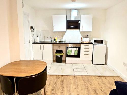 伊肯斯顿Great Value Bath Street Ilkeston Apartment的厨房配有白色橱柜和木桌