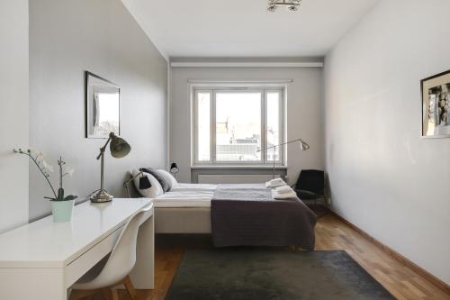赫尔辛基Kotimaailma Apartments Kamppi - 1BR for 3 persons的一间卧室配有一张床、一张书桌和一个窗户。