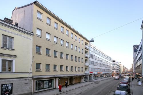 赫尔辛基Kotimaailma Apartments Kamppi - 1BR for 3 persons的城市街道上一座有停车车的建筑