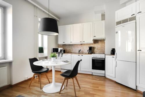 赫尔辛基Kotimaailma Apartments Kamppi - spacious 1BR的厨房配有白色橱柜和白色的桌椅