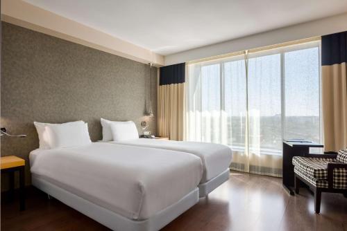 海牙海牙NH酒店的一张大白色的床,位于一个设有大窗户的房间