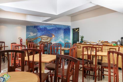 乌贝兰迪亚Lym Flat Hotel的餐厅设有木桌和椅子,墙上挂有绘画作品