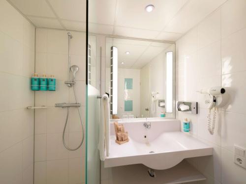 马斯特里赫特马斯特里赫特诺富特酒店的白色的浴室设有水槽和淋浴。