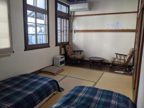 高山Guesthouse Tomaru的一间卧室配有两张床、一张桌子和两把椅子
