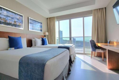 曼塔Wyndham Manta Sail Plaza Hotel and Convention Center的酒店客房配有两张床和一张书桌