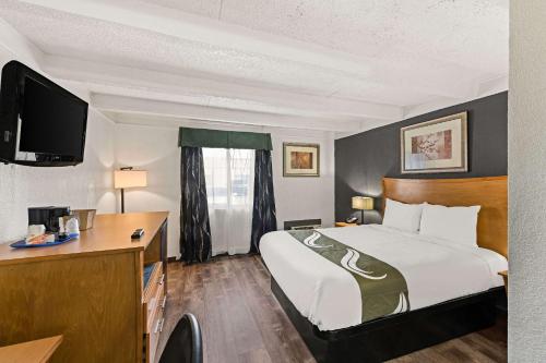康瑟尔布拉夫斯Quality Inn & Suites near I-480 and I-29的配有一张床和一张书桌的酒店客房