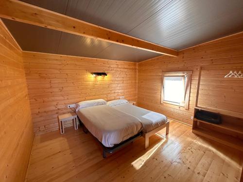 MendexaCamping & Bungalows Leagi的木制客房内的一间卧室,配有一张床