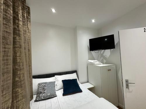 LewishamSmart Cosy/Small Double Room in Oakridge Road Bromley的一间卧室配有一张带两个枕头的床和电视。