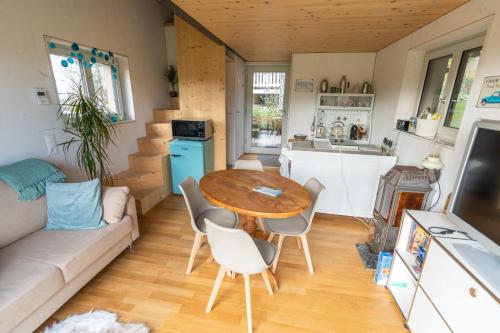 布鲁格Tiny House Chez Claudine with Garden, Workspace, Netflix, free Parking & Wifi的厨房以及带桌椅的起居室。