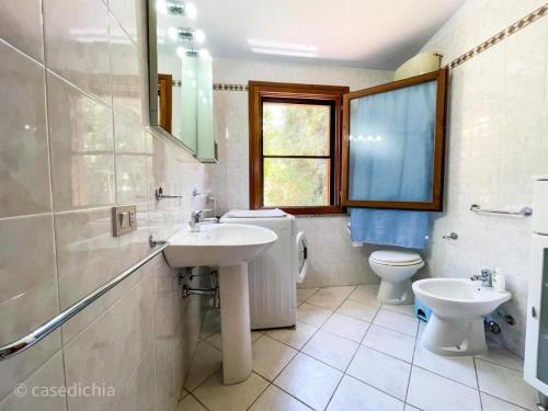 奇亚Torre di Chia Holiday Home的一间带水槽和卫生间的浴室以及窗户。