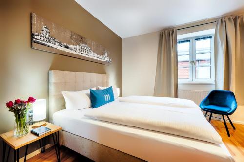 柏林martas Hotel Berlin-Mitte的一间卧室配有一张大床和一张蓝色椅子