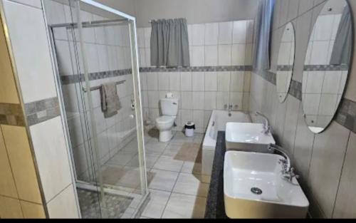 MkuzeUmkhaya Lodge的一间带两个盥洗盆、淋浴和卫生间的浴室