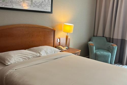 希灵登Colnbrook Hotel London Heathrow Airport的一间卧室配有一张床、一把椅子和一盏灯