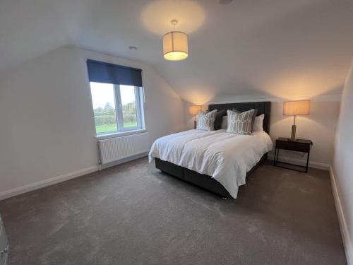 邓博因Modern Dunboyne Home的白色的卧室设有一张大床和一个窗户