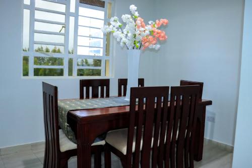 MeruMeru Heights Luxury Apartments的餐桌和椅子,花瓶