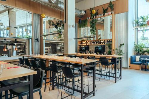 里尔JOST Hôtel Lille Centre的餐厅设有木桌和椅子,种有植物