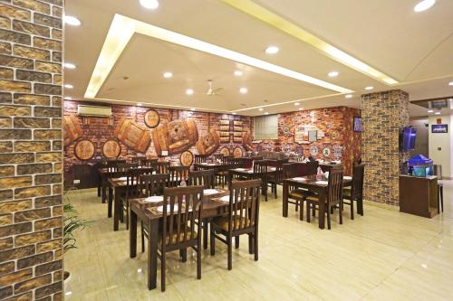 新德里Hotel D'Capitol - Delhi Airport的餐厅设有木桌和椅子,拥有砖墙