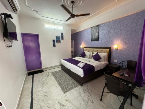 瑞诗凯诗Live Free Hostel Rishikesh的一间卧室配有一张紫色墙壁的床和一张桌子