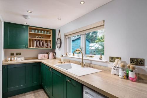 奥赫特拉德The Tranquil Auchterarder 3-bed Cottage的厨房配有绿色橱柜、水槽和窗户