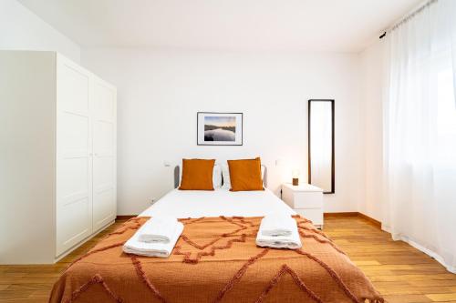 布拉加Flat Armada II - Apartamento T5 junto ao BragaParque的白色卧室配有带橙色枕头的大床