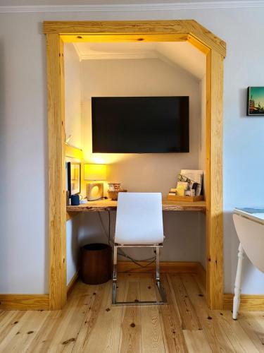 罗登La Petite Auberge Sur Queen的客房设有一张桌子、一把椅子和一台电视