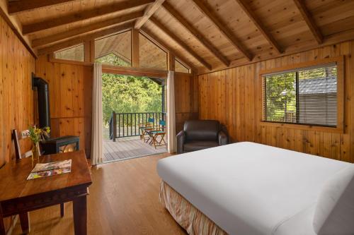 CapitanEl Capitan Canyon的一间带一张床和一张书桌的卧室以及一个阳台