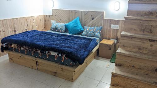 卡索尔MOKSHA COTTAGES AND WOODHOUSE的一间卧室配有一张带蓝色棉被的木床
