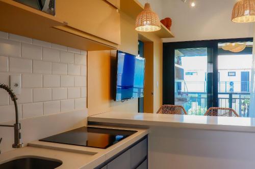 马塔迪圣若昂Lindo Quarto & Sala + SofaCama的一个带水槽的厨房和墙上的电视