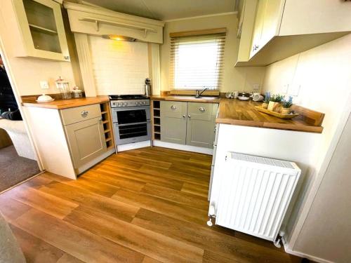 PorchfieldIdyllic mobile home in beautiful surroundings的厨房铺有木地板,配有炉灶烤箱