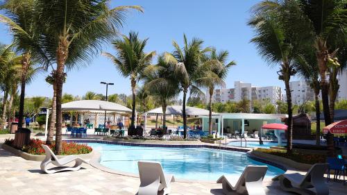 卡达斯诺瓦斯LAGOA QUENTE FLATS的度假村内一座种有棕榈树和椅子的游泳池