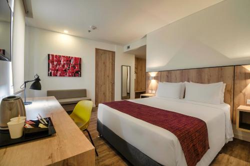 波哥大Hotel Distrito ZF的酒店客房设有一张大床和一张书桌。