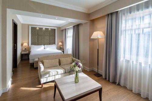 拉科鲁尼亚NH Collection A Coruña Finisterre的酒店客房配有床、沙发和桌子。