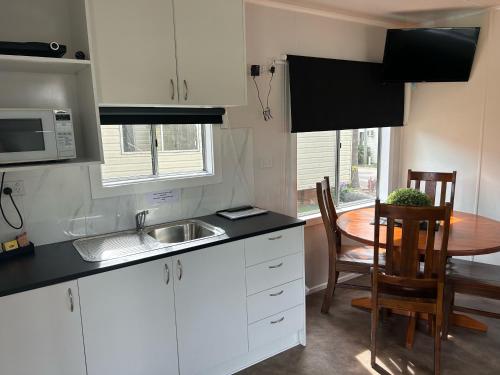 巴特曼斯贝Batemans Bay Holiday Park & Hostel的厨房配有白色橱柜、桌子和水槽。