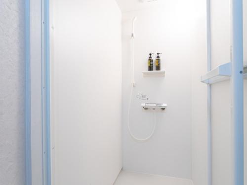 萨摩川内市HOTEL Tsuru Sendai的白色的浴室设有淋浴,在架子上装有瓶子