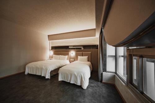高雄高雄旅居文旅一心馆 的配有白色床单的酒店客房内的两张床