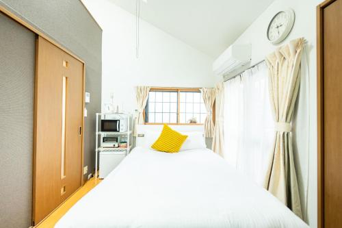 福冈Rooms箱崎的卧室配有一张床,墙上挂着一个钟