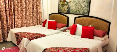 卧佛Forest Paradise Inn Teluk Bahang PRIVATE MALAY TRADITIONAL HOUSE CONCEPT HOTEL的两张位于酒店客房的床铺,配有红色枕头