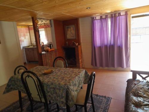 Las CompuertasEL LOTE DE VERO的一间设有桌子和紫色窗帘的用餐室