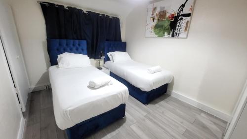 伦敦Garland Modern Close To Station 3 Bedroom City Apartment的蓝色和白色的客房内的两张床